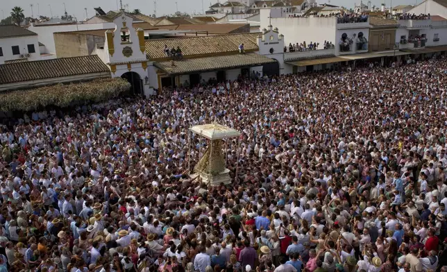 Pilgrims gather during the procession of the Virgin of El Rocio in the village of El Rocio, near Almonte in southern Spain, Monday, June 9, 2025, during the annual pilgrimage in which devotees of the Virgin converge on the shrine. (AP Photo/Emilio Morenatti)