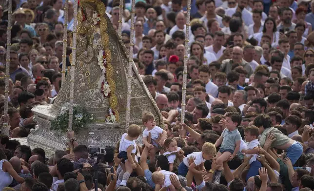 Children are carried close to the Virgin of El Rocio during a procession in the village of El Rocio, near Almonte in southern Spain, Monday, June 9, 2025, during the annual pilgrimage in which devoteesof the Virgin del Rocio converge on the shrine. (AP Photo/Emilio Morenatti)