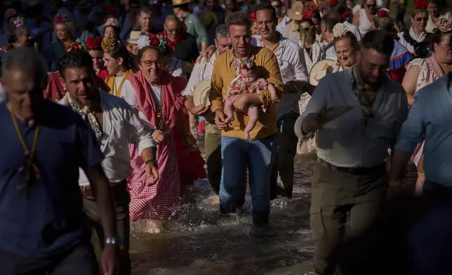 Pilgrims cross the Quema River on their way to the shrine of El Rocio near Aznalcazar, Spain, Thursday, June 5, 2025, during the annual pilgrimage in which devoteesof the Virgin del Rocio converge at the shrine. (AP Photo/Emilio Morenatti)