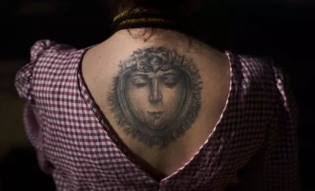 A tattoo of the Virgin of El Rocio covers the back of Paloma Maria, a pilgrim from Cordoba, who crosses the Quema River near Aznalcazar, Spain, a crucial point in the annual Catholic pilgrimage to the shrine of the Virgin of El Rocio, Thursday, June 5, 2025. (AP Photo/Emilio Morenatti)