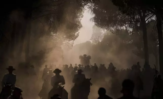 Pilgrims walk through dusty terrain near Aznalcazar, Spain, during the annual Catholic pilgrimage to the shrine of the Virgin of El Rocio, Friday, June 6, 2025. (AP Photo/Emilio Morenatti)