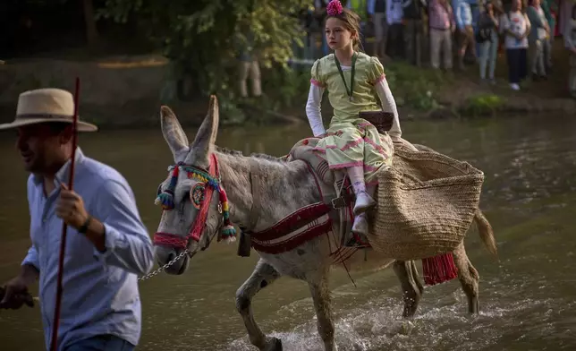 Pilgrims cross the Quema River near Aznalcazar, Spain, a crucial point in the annual Catholic pilgrimage to the shrine of the Virgin of El Rocio that draws hundreds of thousands of faithful, Friday, June 6, 2025. (AP Photo/Emilio Morenatti)