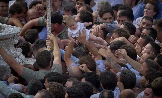 A baby is lifted to be close to the Virgin of El Rocio during a procession in the village of El Rocio, near Almonte in southern Spain, Monday, June 9, 2025, during the annual pilgrimage in which devoteesof the Virgin converge on the shrine. (AP Photo/Emilio Morenatti)