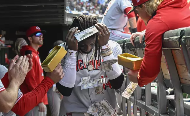 Cincinnati Reds' Elly De La Cruz is showered with fake money in the dugout after he hit a two-run home run during the sixth inning of a baseball game against the Chicago Cubs, Sunday, June 1, 2025, in Chicago. (AP Photo/Matt Marton)