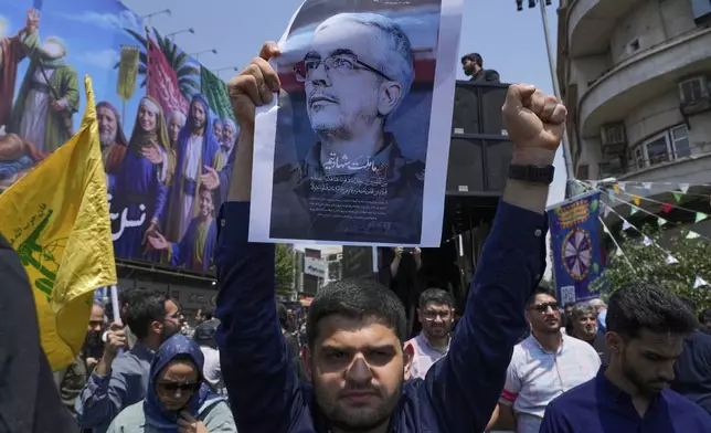 An Iranian protester holds up a poster of Chief of General Staff of the Armed Forces Mohammad Bagheri, who was killed in an Israeli strike, in an anti-Israeli gathering in Tehran, Iran, Friday, June 13, 2025. (AP Photo/Vahid Salemi)