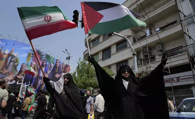 Iranian protesters hold up Iranian and Palestinian flags in an anti-Israeli gathering in Tehran, Iran, Friday, June 13, 2025. (AP Photo/Vahid Salemi)