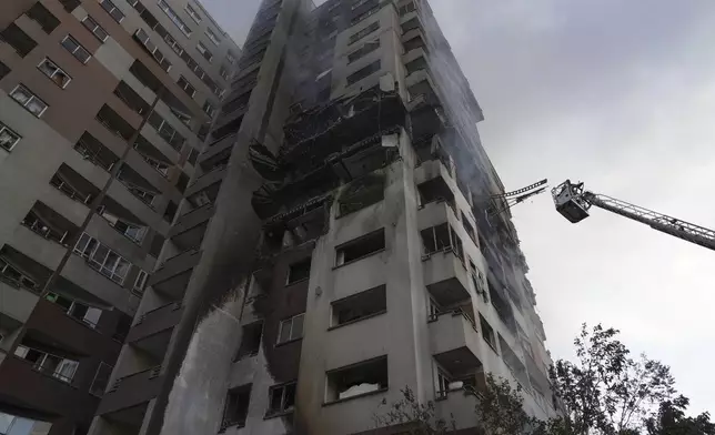 A firefighter stands on a crane at the scene of an explosion at a residence compound after Israeli attacks in Tehran, Friday, June 13, 2025. (AP Photo/Vahid Salemi)