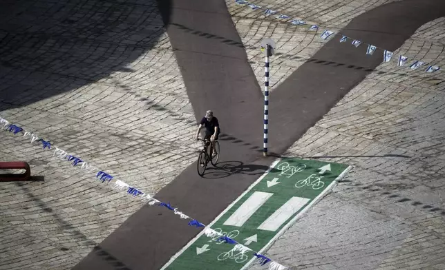 A man rides a bicycle along the empty promenade on Tel Aviv's beachfront, Friday, June 13, 2025. (AP Photo/Leo Correa)