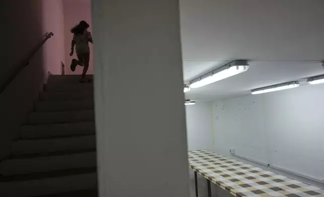 A girl runs to a bomb shelter in an apartment building in Hadera, Israel, Friday June 13, 20025. (AP Photo/Ariel Schalit)