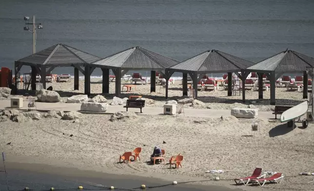 A man sits on the empty beach along Tel Aviv's beachfront, Friday, June 13, 2025. (AP Photo/Leo Correa)