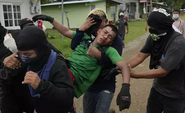 Men carry a fellow demonstrator injured during clashes with police at a protest against recent actions by President Jose Raul Mulino, including a pension reform law and a security agreement with the United States involving the Panama Canal, in Arimae, Panama, Thursday, June 5, 2025. (AP Photo/Matias Delacroix)