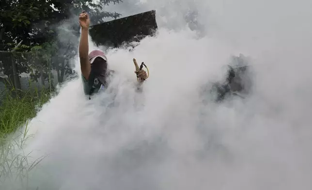 Tear gas enugulf anti-government protesters as they clash with police at the Indigenous Embera community of Arimae, Panama, Thursday, June 5, 2025. (AP Photo/Matias Delacroix)