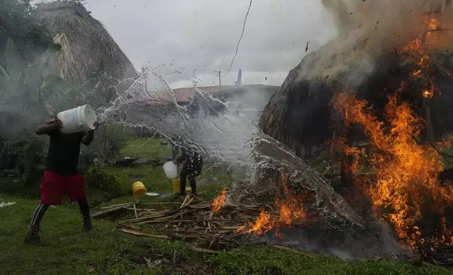 Residents try to extinguish a hut that caught fire during clashes between anti-government protesters and police in the Indigenous Embera community of Arimae, Panama, Thursday, June 5, 2025. (AP Photo/Matias Delacroix)