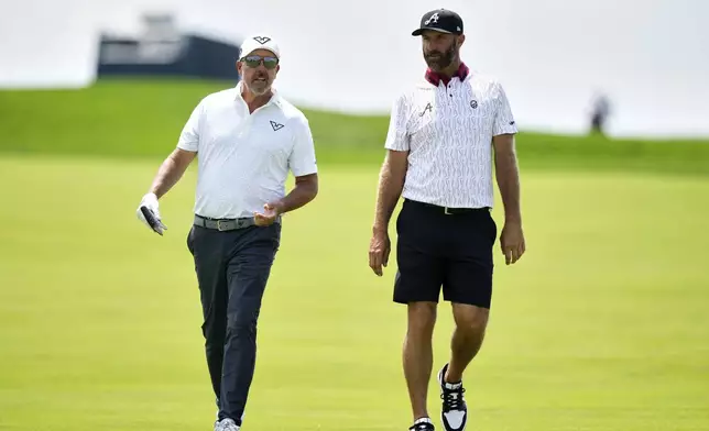 Dustin Johnson, right, and Phil Mickelson talk as they walk down the 12th fairway during a practice round ahead of the U.S. Open golf tournament at Oakmont Country Club Tuesday, June 10, 2025, in Oakmont, Pa. (AP Photo/Charlie Riedel)