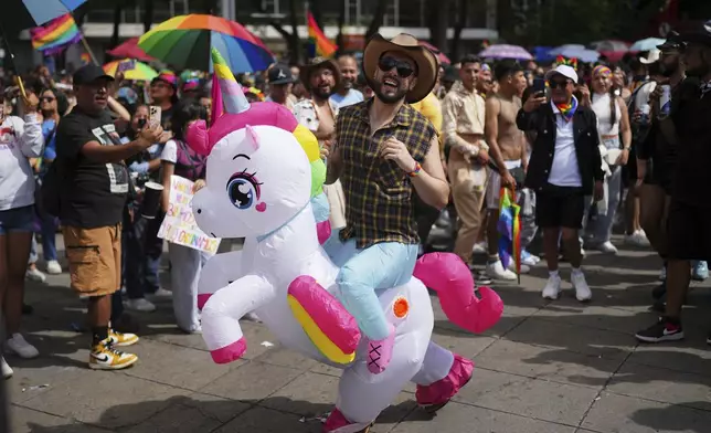 A participant rides on the back of a fellow participant wearing a unicorn costume in the annual Pride Parade in Mexico City, Saturday, June 28, 2025. (AP Photo/Eduardo Verdugo)