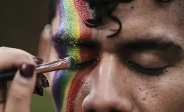 A reveler gets made up before the start the annual Pride parade marking LGBTQ+ Pride month in Bogota, Colombia, Sunday, June 29, 2025. (AP Photo/Ivan Valencia )