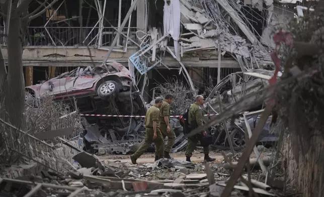 Israeli security forces inspect destroyed residential buildings that were hit by a missile fired from Iran, in Ramat Gan, near Tel Aviv, Israel, on Saturday, June 14, 2025. (AP Photo/Ariel Schalit)