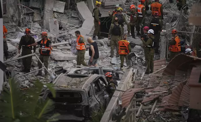 Israeli security forces inspect destroyed houses that were struck by a missile fired from Iran, in Rishon Lezion, Israel on Saturday, June 14, 2025. (AP Photo/Ohad Zwigenberg)