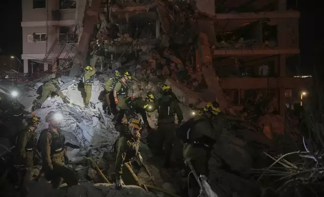 Israeli security forces inspect destroyed buildings that were hit by a missile fired from Iran, near Tel Aviv, Israel, Sunday, June 15, 2025. (AP Photo/Ohad Zwigenberg)