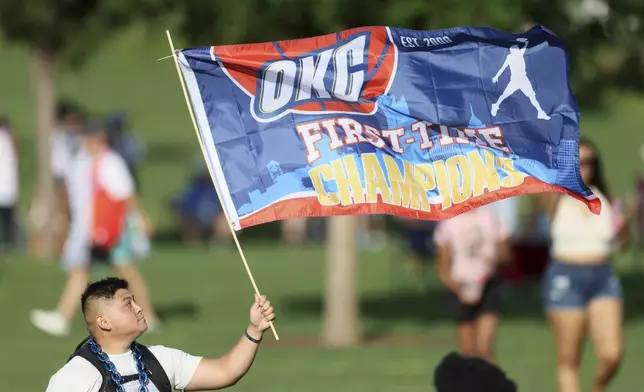 A fan holds a flag before a celebration of the Oklahoma City Thunder's NBA basketball championship Tuesday, June 24, 2025, in Oklahoma City. (AP Photo/Nate Billings)