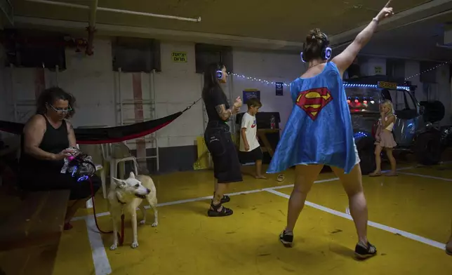 People dance during a headphones party inside an underground parking lot used as a shelter against potential missile strikes from Iran, in Tel Aviv, Israel, Monday, June 23, 2025. (AP Photo/Oded Balilty)