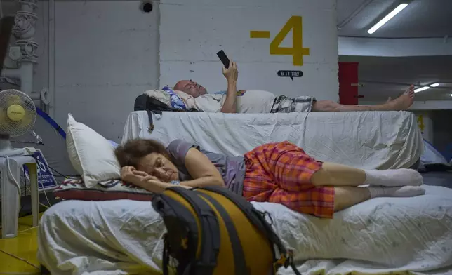 People spend the night in an underground parking garage as a precaution against possible Iranian missile attacks, in Tel Aviv, Israel, Monday, June 23, 2025. (AP Photo/Ohad Zwigenberg)