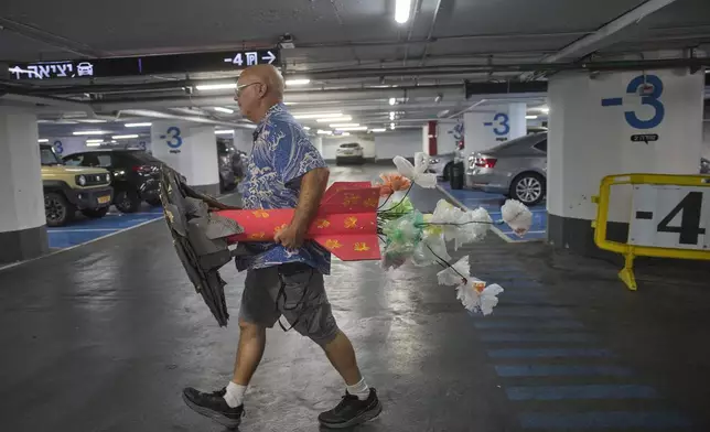 A man carries a mock rocket in a underground parking garage which people used it to take shelter as a safety precaution after a ceasefire was announced, in Tel Aviv, Israel, Tuesday, June 24, 2025. (AP Photo/Ohad Zwigenberg)
