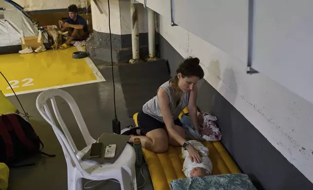People shelter in an underground parking in Tel Aviv, Israel, Thursday, June 19, 2025. (AP Photo/Bernat Armangue)