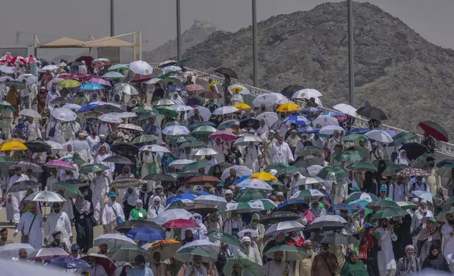 FILE - Muslim pilgrims use umbrellas to shield themselves from the sun as they arrive to cast stones at pillars in the symbolic stoning of the devil during the annual hajj, in Mina, near the holy city of Mecca, Saudi Arabia, Tuesday, June 18, 2024. (AP Photo/Rafiq Maqbool, File)