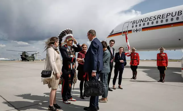 German Chancellor Friedrich Merz, centre, is greeted by Steven Crowchild, second left, of the Tsuut'ina First Nation, as he arrives in Calgary, Alberta, Sunday, June 15, 2025, to attend the G7 Leaders meeting taking place in Kananaskis. (Jeff McIntosh/The Canadian Press via AP)