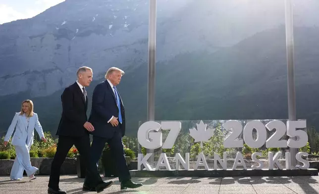 President Donald Trump walks with Canada's Prime Minister Mark Carney after a group photo at the G7 Summit, Monday, June 16, 2025, in Kananaskis, Canada, as Italy's Prime Minister Giorgia Meloni follows. (AP Photo/Mark Schiefelbein)