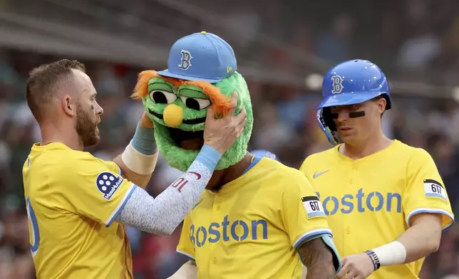 Boston Red Sox's Trevor Story, left, places a mascot head on teammate Ceddanne Rafaela after Rafaela hit a home run during the sixth inning of a baseball game against the Toronto Blue Jays, Saturday, June 28, 2025, in Boston. (AP Photo/Mark Stockwell)