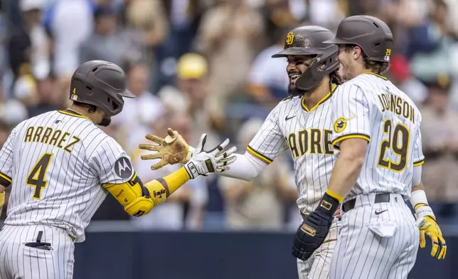 San Diego Padres' Luis Arraez (4) and Bryce Johnson (29) celebrate a home run by Fernando Tatis Jr., center, in the seventh inning of a baseball game against the Kansas City Royals, Saturday, June 21, 2025, in San Diego. (AP Photo/Tony Ding)