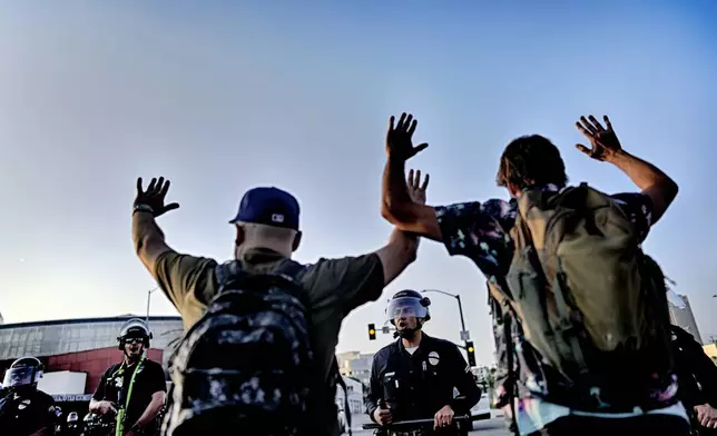 Los Angeles police officers with batons and riot gear attempt to move back protesters in downtown Los Angeles on Monday, June 9, 2025. (AP Photo/Eric Thayer)