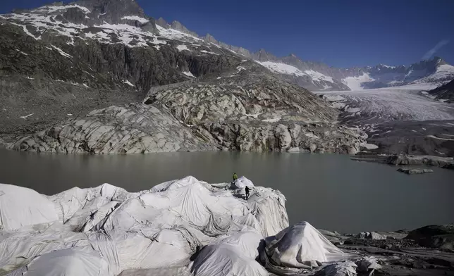 Workers prepare sheets to cover the Rhone Glacier near Goms, Switzerland, June 10, 2025. (AP Photo/Matthias Schrader)