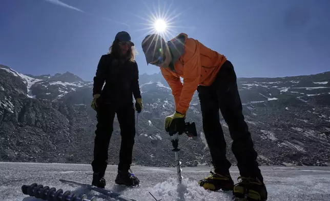 Matthias Huss, of the Federal Institute of Technology in Zurich and glacier monitoring group GLAMOS, drills holes into the Rhone Glacier near Goms, Switzerland, June 10, 2025. (AP Photo/Matthias Schrader)