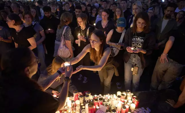 People light candles for victims of a former student who opened fire at a school, fatally wounding 10 people and injuring many others before taking his own life, in Graz, Austria, Tuesday, June 10, 2025. (AP Photo/Darko Bandic)