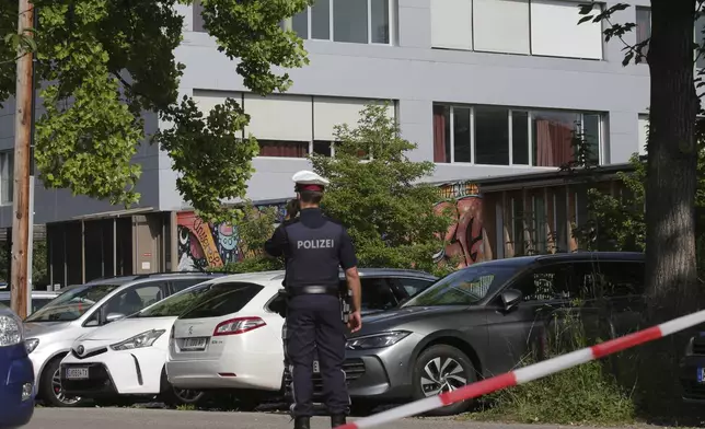 A police officer makes a phone call in front of a school building after a shooting Graz, Austria, Tuesday, June 10, 2025. (AP Photo/Heinz-Peter Bader)