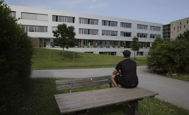 Marvin, second name not given, sits on a table and prays for the victims in front of a school building, after a shooting at the school in Graz, Austria, Tuesday, June 10, 2025. (AP Photo/Heinz-Peter Bader)
