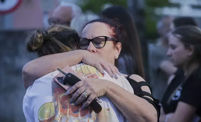 Women embrace each other as they commemorate the victims of a deadly shooting at the school in Graz, Austria, Tuesday, June 10, 2025. (AP Photo/Heinz-Peter Bader)