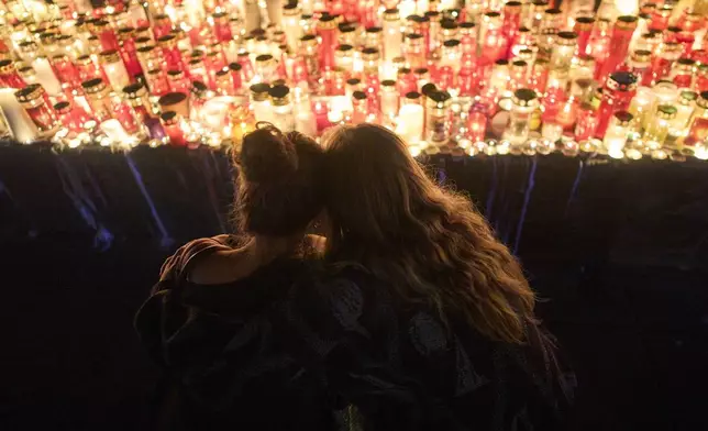 Women look at candles for victims of a former student who opened fire at a school, fatally wounding 10 people and injuring many others before taking his own life, in Graz, Austria, Tuesday, June 10, 2025. (AP Photo/Darko Bandic)
