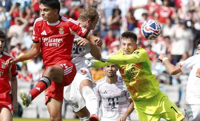 Bayern Munich's Harry Kane misses a header between Benfica's Joao Rego and goalkeeper Anatoliy Trubin during the Club World Cup Group C soccer match between Benfica and Bayern Munich in Charlotte, N.C., Tuesday, June 24, 2025. (AP Photo/Nell Redmond)