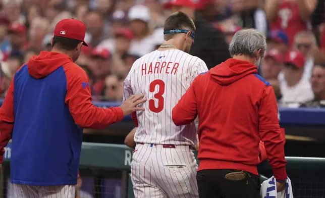 FILE - Philadelphia Phillies' Bryce Harper is led to the dugout after being hit by a pitch from Atlanta Braves' Spencer Strider plays during a baseball game, Tuesday, May 27, 2025, in Philadelphia. (AP Photo/Matt Slocum)