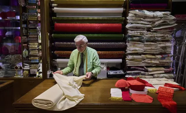 FILE - Italian tailor Raniero Mancinelli, 87, prepares the white fabric to create suits, in three different sizes, to be taken to the Vatican in the hope that it might be worn by the new pope, at his shop in Rome, April 24, 2025. (AP Photo/Bernat Armangue, File)