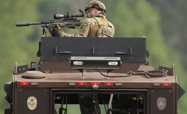 A law enforcement officer trains his rifle towards a house as the officers search for shooting suspect, Vance Boelter, Sunday, June 15, 2025, in Belle Plaine, Minn. (AP Photo/George Walker IV)