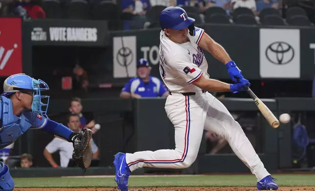 Texas Rangers' Wyatt Langford hits a double that scored teammate Sam Haggerty in front of Kansas City Royals catcher Freddy Fermin during the first inning of a baseball game, Wednesday, June 18, 2025, in Arlington, Texas. (AP Photo/LM Otero)