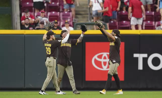 San Diego Padres' Bryce Johnson (29), Jackson Merrill, center, and Fernando Tatis Jr. celebrate following a baseball game against the Cincinnati Reds, Saturday, June 28, 2025, in Cincinnati. (AP Photo/Jeff Dean)