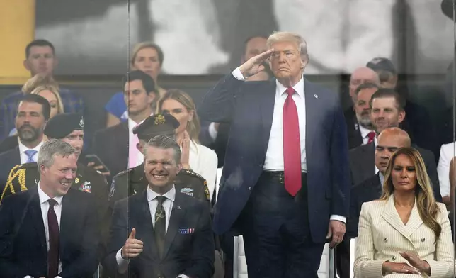 President Donald Trump salutes as attends a military parade commemorating the Army's 250th anniversary, coinciding with his 79th birthday, Saturday, June 14, 2025, in Washington, as Secretary of the Army Daniel Driscoll, Defense Secretary Pete Hegseth, and first lady Melania Trump, watch. (AP Photo/Julia Demaree Nikhinson)