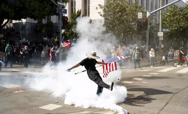 A demonstrator kicks a canister of tear gas during a protest Saturday, June 14, 2025, in Los Angeles. (AP Photo/Noah Berger)