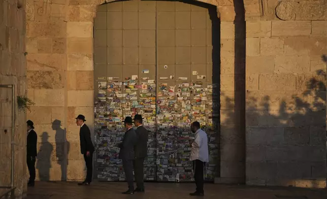Ultra-Orthodox Jewish men pray next to the closed Jaffa Gate just outside Jerusalem's Old City following a ban on public gatherings imposed by Israel's Home Front Command after a military strike on Iran, Friday, June 13, 2025. (AP Photo/Ohad Zwigenberg)